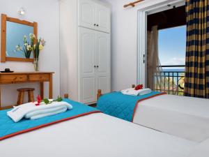 two beds in a bedroom with a balcony at Calypso Studios in Amoudi