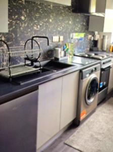 a kitchen with a sink and a washing machine at The Wee Bunker in Barassie