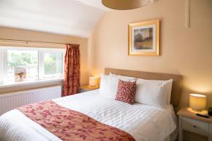 a bedroom with a bed and a window at Pettifers Freehouse Hotel in Crudwell