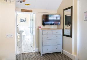 a bathroom with a dresser with a tv on a wall at Pettifers Freehouse Hotel in Crudwell