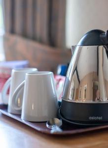 a toaster on a plate with two cups on a table at Pettifers Freehouse Hotel in Crudwell