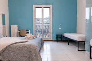 a blue room with two beds and a window at Saragozza Apartments in Bologna