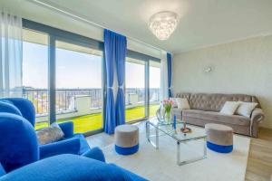 a living room with blue furniture and a large window at MF Lux Penthouse in Siófok