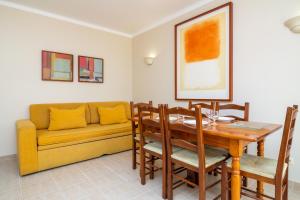 a dining room with a table and a couch at Vila do Castelo in Albufeira