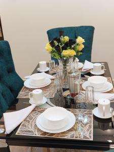 a table with white plates and a vase of flowers at Kaisa gardens in Nairobi