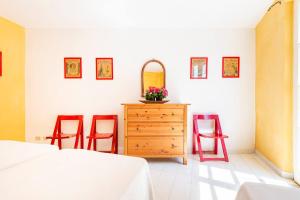 a bedroom with two red chairs and a dresser with a mirror at The Old Mill with Private Garden and Torrent in Portoferraio