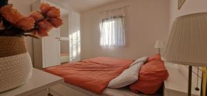 a bedroom with a bed with orange sheets and a window at SWIM and CLIMB BAŠKA HOLIDAY HOUSE - island KRK in Draga