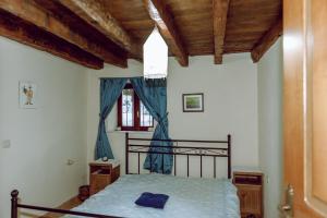 Schlafzimmer mit einem Bett mit blauer Bettwäsche und einem Fenster in der Unterkunft To Petrino 