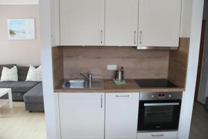 a kitchen with white cabinets and a sink at Ort Lemkenhafen Bolle in Fehmarn +13 photos