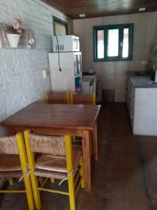 cocina con mesa de madera con sillas y nevera en La Casita en Chascomús