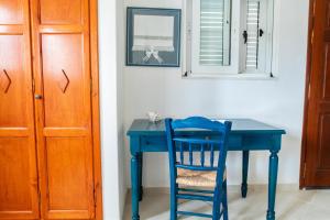 uma mesa azul com uma cadeira azul e um espelho em Ficus Traditional Apartments em Kefalos