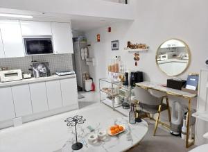 a white kitchen with a table and a mirror at Angel House in Daegu