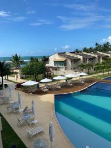 a swimming pool with chairs and umbrellas and a resort at Ekoara Residence - Muro Alto in Porto De Galinhas