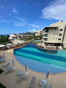 a large swimming pool with chairs and a building at Ekoara Residence - Muro Alto in Porto De Galinhas