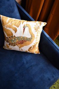 a pillow with a bird on it sitting on a blue couch at Le Cheval Blanc - Lac du Der - Logis Hotel in Giffaumont