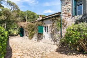 an old stone house with green shutters on a street at The Old Mill with Private Garden and Torrent in Portoferraio
