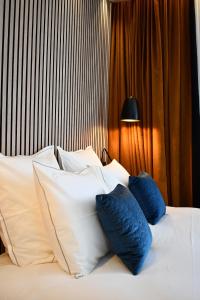 a bed with blue and white pillows on it at Le Cheval Blanc - Lac du Der - Logis Hotel in Giffaumont