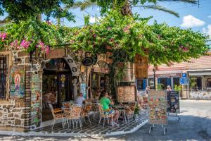a woman sitting at a table outside of a restaurant at Casa Christiana, Lardos in Lartos
