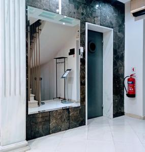 ein Badezimmer mit zwei Spiegeln und einem Feuerlöscher in der Unterkunft Hotel Solomou Athens in Athen