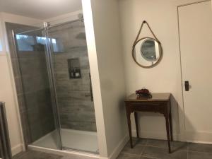 a bathroom with a shower with a mirror and a table at La Maison Bellemare in Saint-Jean-des Piles