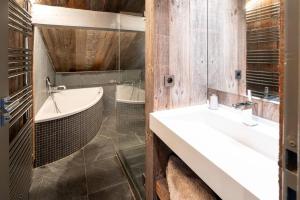 ペイゼ・ナンクロワにあるMasara - 5-room chalet plus sauna and jacuzzi 12 pの洗面台2つとバスタブ付きのバスルーム