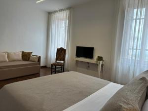 a bedroom with a bed and a couch and a tv at RESIDENCE IL GROTTINO in Gualdo Cattaneo