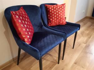 a blue chair with two red pillows on it at Apartment Central Park in Daugavpils