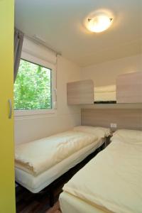 Cette chambre comprend 3 lits et une fenêtre. dans l'établissement Ideal Camping Lampele GmbH, à Ossiach