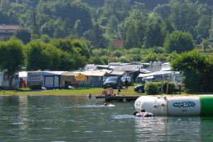 un groupe de personnes nageant dans l'eau près d'un terrain de camping dans l'établissement Ideal Camping Lampele GmbH, à Ossiach