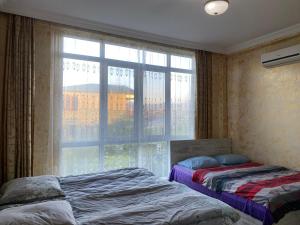 a bedroom with two beds and a large window at Merab House in Batumi