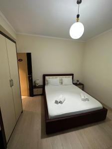 a bedroom with a bed with white sheets and a light at Grand Park Hotel in Gjirokastër