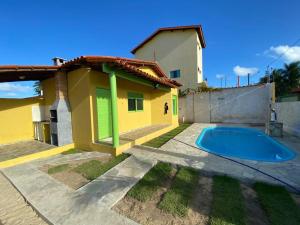 a house with a swimming pool in front of it at Chalé Lagoa do Pau in Coruripe +9 photos