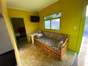 a living room with a couch in a yellow wall at Chalé Lagoa do Pau in Coruripe