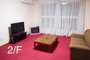 a living room with a couch and a table and a tv at Furano House, JR Station, 2F Apartment, 3 Bedrooms, Max 8PP - 6 Adults 2 Kid, Onsite Parking in Furano