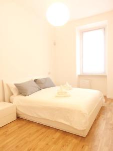 a white bedroom with a large bed and a window at Apartment Ca' de Bezzi in Bolzano
