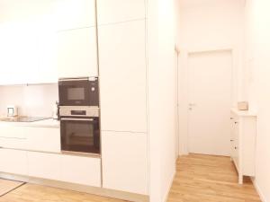 a white kitchen with white cabinets and a microwave at Apartment Ca' de Bezzi in Bolzano