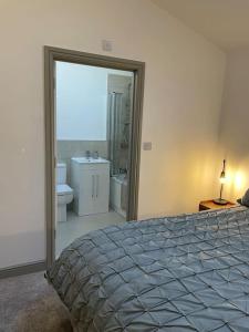 a bedroom with a bed and a bathroom with a sink at Smithy Bungalow, free private parking included, Buxton in Buxton