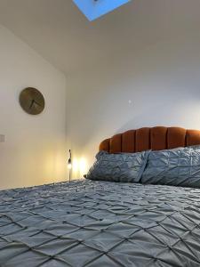 a bedroom with a bed with a clock on the wall at Smithy Bungalow, free private parking included, Buxton in Buxton