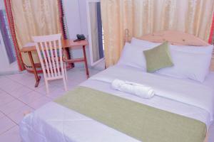 a bedroom with a bed with a chair and a desk at INZOZI AFRICA HOUSE B&B- Kacyiru in Kigali