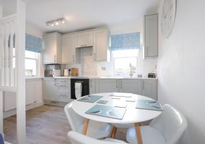 a white kitchen with a white table and chairs at Smugglers Cove in North Berwick