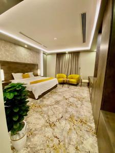 una habitación de hotel con una cama grande y una silla amarilla en Narmiss Aparthotel, en Unaizah