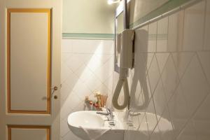 ein Badezimmer mit einem Waschbecken und einem Telefon an der Wand in der Unterkunft Fattoria Guicciardini in San Gimignano