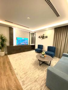 نارميس للشقق الفندقية في عنيزة: غرفة معيشة مع أريكة زرقاء وتلفزيون