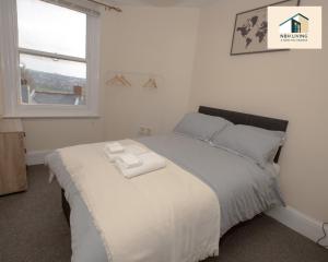 a bedroom with a bed with two towels on it at Three Modern Double Bed Apartment By NBH Living Short Lets & Serviced Accommodation in Brighton & Hove