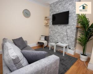 a living room with a couch and a tv on a brick wall at Three Modern Double Bed Apartment By NBH Living Short Lets & Serviced Accommodation in Brighton & Hove