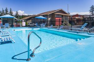 a swimming pool with chairs and umbrellas at Coachman Inn in Bellingham