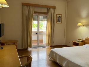 a hotel room with a bed and a sliding glass door at Grande Hotel Dom Dinis in Mirandela