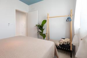 a white bedroom with a bed and a plant at Amici Miei Makarska in Makarska
