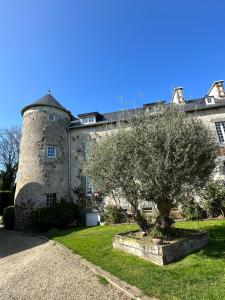 ein altes Schloss mit einem Baum davor in der Unterkunft Manoir de La Ville Durand in Binic