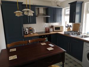 een keuken met donkerblauwe kasten en een houten tafel bij Cosy Town House in Belfast